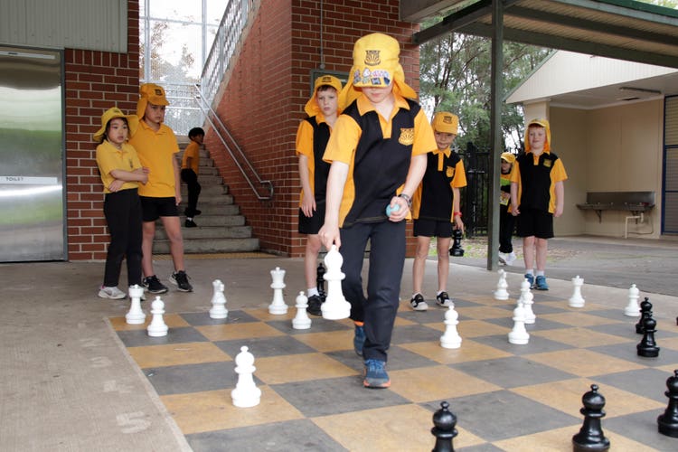 Students playing together on the outdoor giant chessboard area.