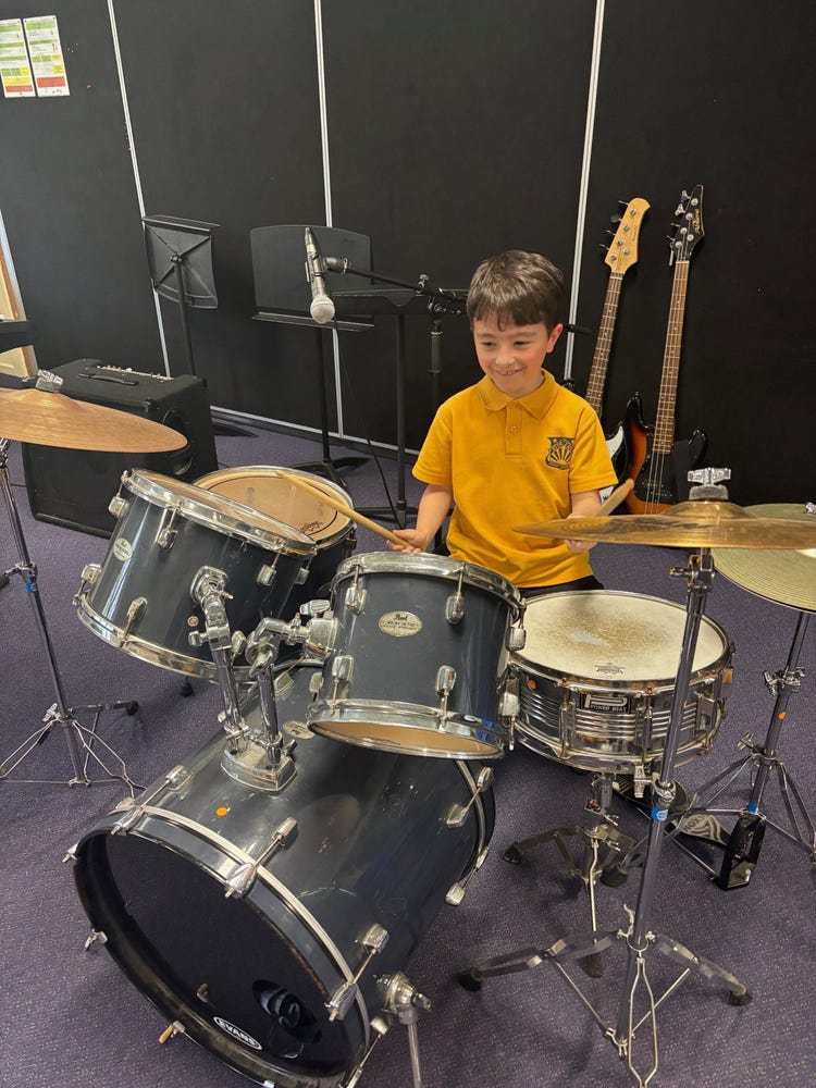Student on drum kit smiling and playing