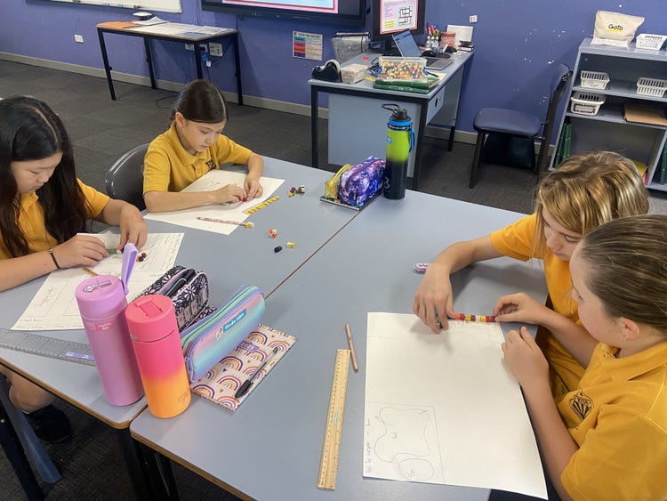 Four senior girls sitting at their desks, focused and engaged in a measuring activity.