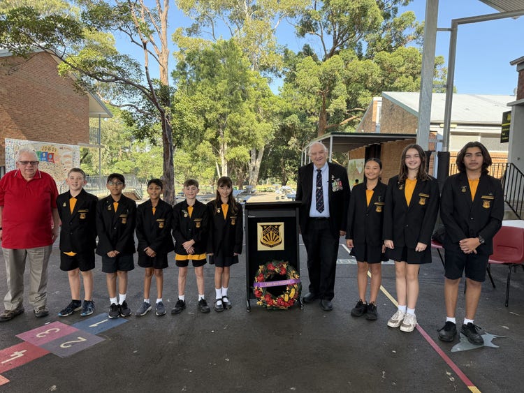 School captains standing with a special guest during the outdoor ANZAC Day assembly.