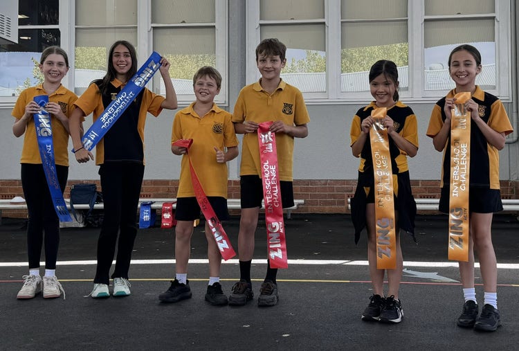 Six smiling students proudly holding their winner sashes after the school dance program,