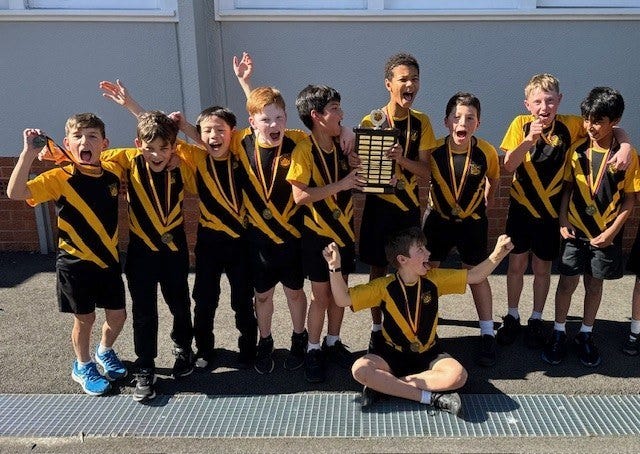 Smiling boys from the school soccer team celebrating their victory, proudly holding trophies and wearing medals.