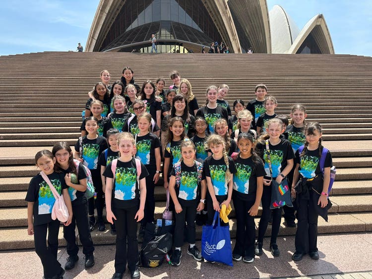 School choir standing on the Opera House steps wearing colourful shirts.